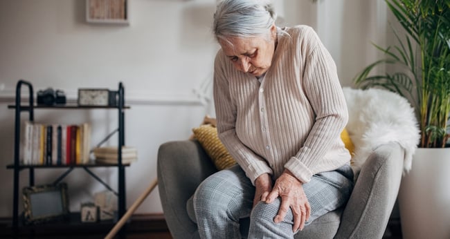 Oudere vrouw die naar knie grijpt