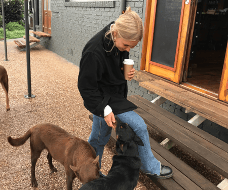 Student en mantelzorger is aan het wandelen met een koffie en haar honden