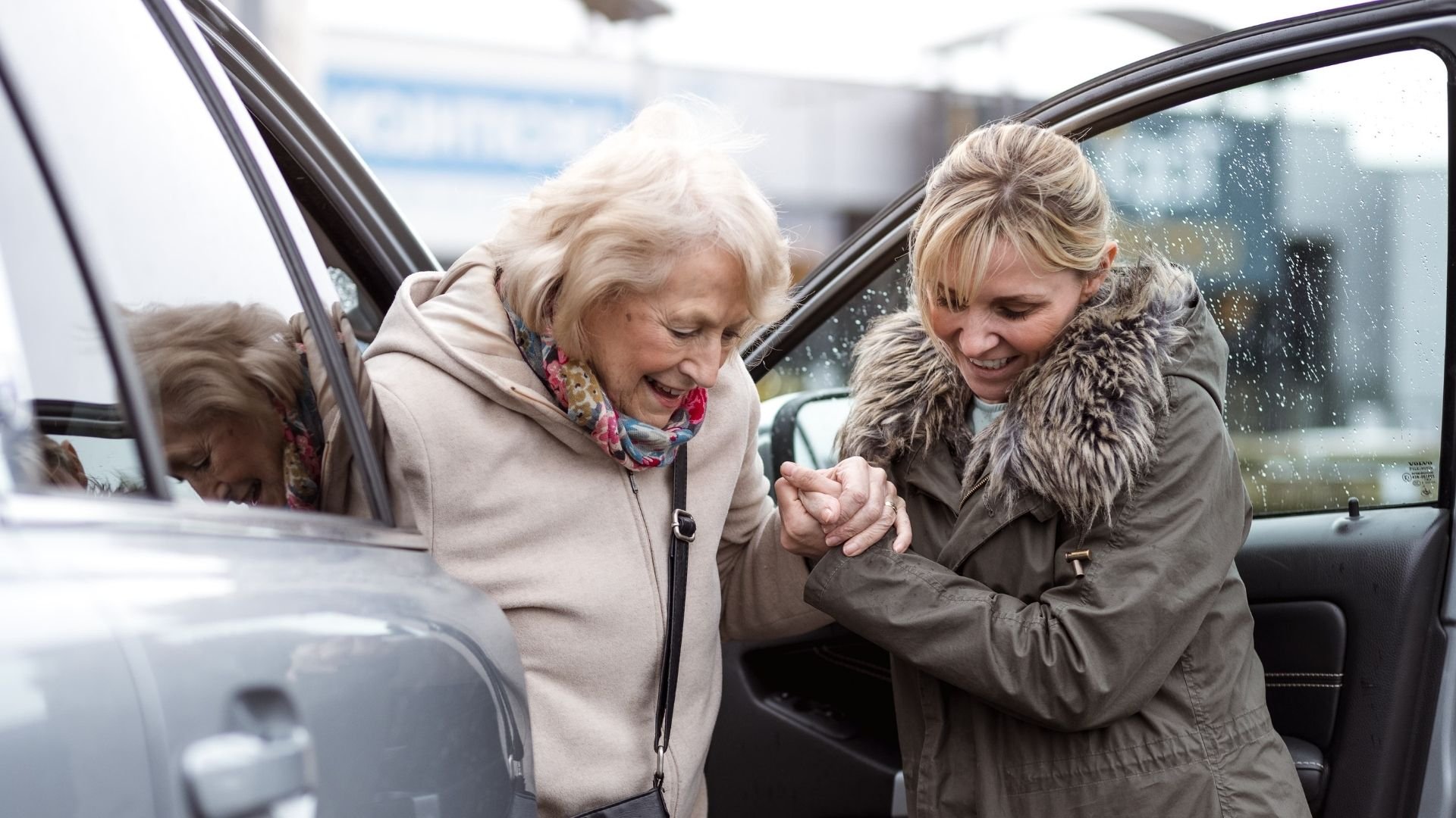 helpper helpt oudere vrouw uit de auto