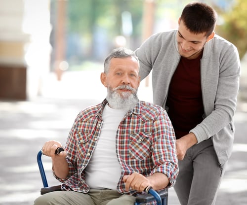 Zoon die zorgt voor vader in rolstoel