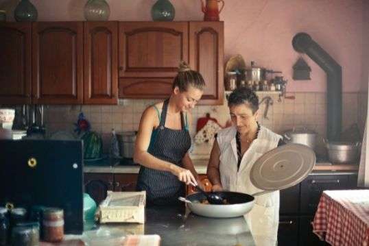 Twee vrouwen met een schort aan zijn samen aan het koken.