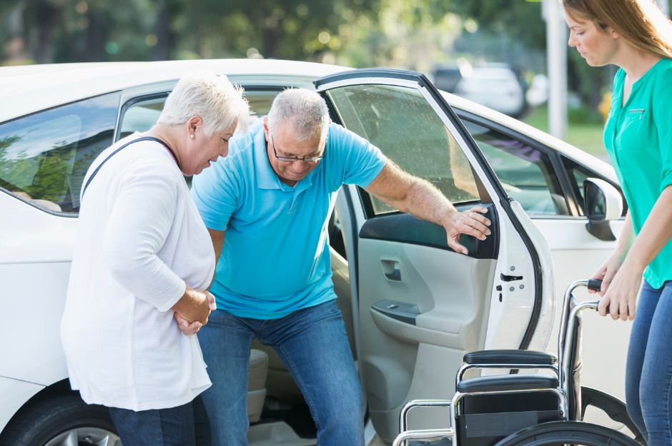 La famille aide le père à sortir de la voiture et le place dans le fauteuil roulant.