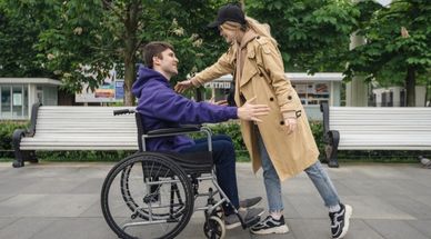 Man in rolstoel is op pad met zijn assistent